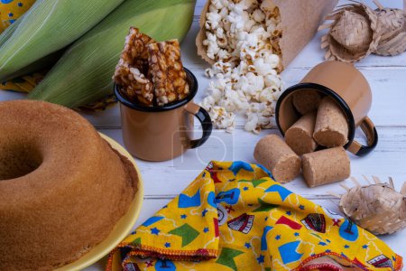 Grüner Mais und Süßigkeiten von der Festa Junina auf weißem Holztisch.