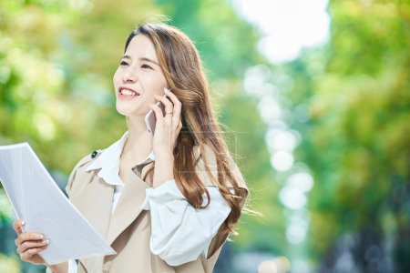 Photo for Young woman talking on smartphone outdoors - Royalty Free Image