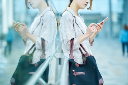 Photo for A young woman looking at a smartphone screen with a troubled expression - Royalty Free Image