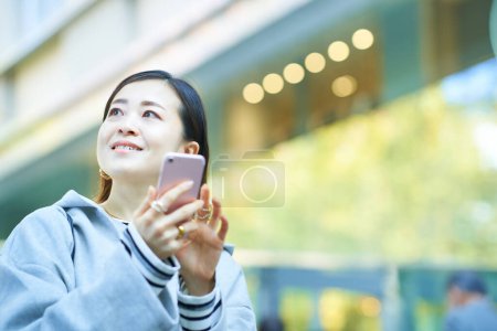 Téléchargez les photos : Femme regardant l'écran du smartphone à l'extérieur - en image libre de droit