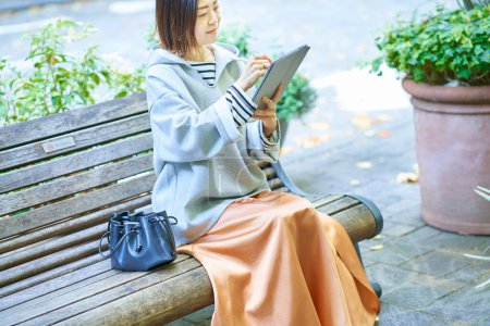 Foto de Mujer asiática en ropa casual operando una tableta PC - Imagen libre de derechos
