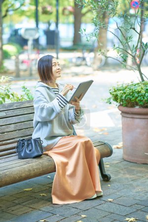 Téléchargez les photos : Femme asiatique en vêtements décontractés opérant une tablette PC - en image libre de droit