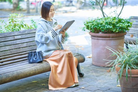 Foto de Mujer asiática en ropa casual operando una tableta PC - Imagen libre de derechos