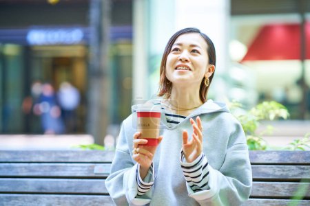Téléchargez les photos : Femme buvant du café avec une expression détendue à l'extérieur - en image libre de droit