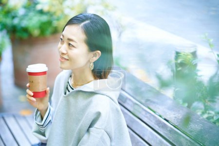 Photo for Woman drinking coffee with a relaxed expression outdoors - Royalty Free Image