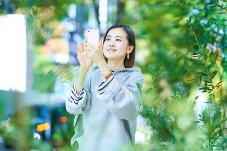 Téléchargez les photos : Jeune femme tenant smartphone en plein air - en image libre de droit