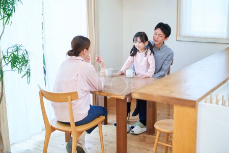 Téléchargez les photos : Parents et leur enfant parlent heureux dans le salon - en image libre de droit