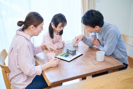 Téléchargez les photos : Une famille discute en regardant un modèle de maison individuelle - en image libre de droit