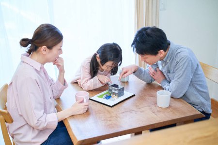 Foto de Una familia discutiendo mientras mira un modelo de una casa unifamiliar - Imagen libre de derechos