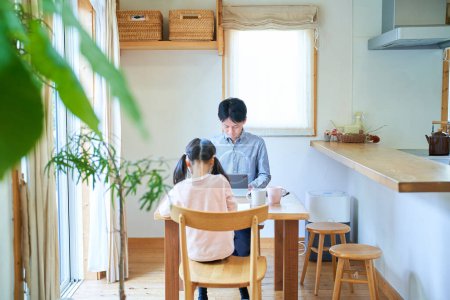 Photo for Girl drawing with her father working at the table at home - Royalty Free Image