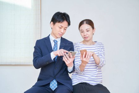 Téléchargez les photos : Un couple consultant tout en regardant un écran de smartphone dans la chambre - en image libre de droit