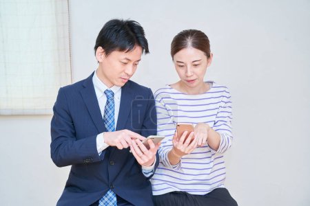 Foto de Una pareja consultando mientras mira la pantalla de un teléfono inteligente en la habitación - Imagen libre de derechos