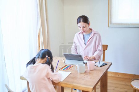Téléchargez les photos : Fille dessin avec sa mère travaillant à la table à la maison - en image libre de droit
