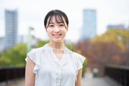 Photo for Asian young woman smiling and standing outdoors - Royalty Free Image
