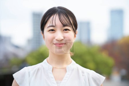 Photo for Asian young woman smiling and standing outdoors - Royalty Free Image
