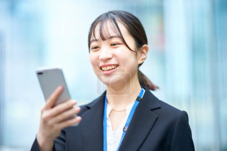Photo for Young woman in suit looking at the screen of smartphone - Royalty Free Image