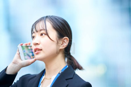 Téléchargez les photos : Asiatique jeune femme dans un costume parler sur un smartphone - en image libre de droit