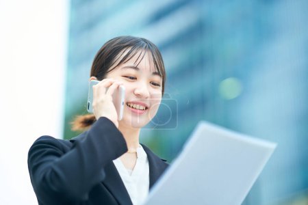 Photo for Asian young woman in a suit talking on a smartphone - Royalty Free Image