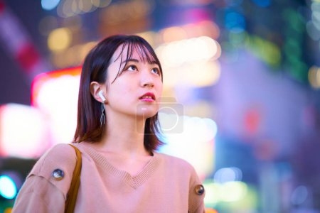 Photo for Asian young woman standing in downtown at night - Royalty Free Image