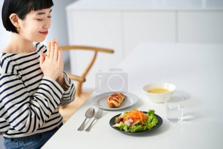Téléchargez les photos : Femme commençant un repas dans la salle à manger à la maison - en image libre de droit