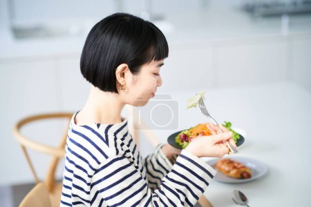Foto de Mujer joven comiendo en casa cenando - Imagen libre de derechos