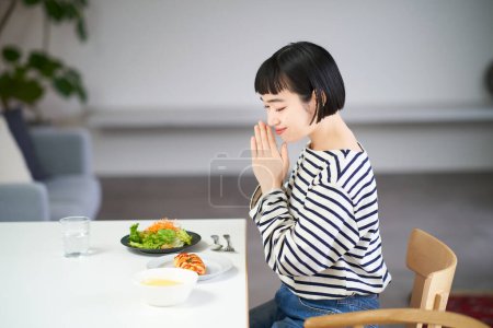 Photo for Woman starting a meal in the dining room at home - Royalty Free Image