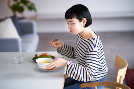 Foto de Mujer joven comiendo en casa cenando - Imagen libre de derechos