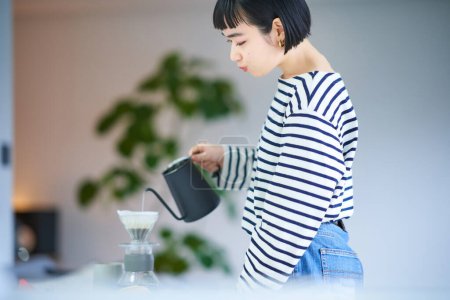Photo for Young woman brewing coffee in her room - Royalty Free Image