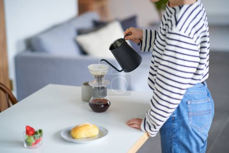 Téléchargez les photos : Jeune femme brassant du café dans sa chambre - en image libre de droit