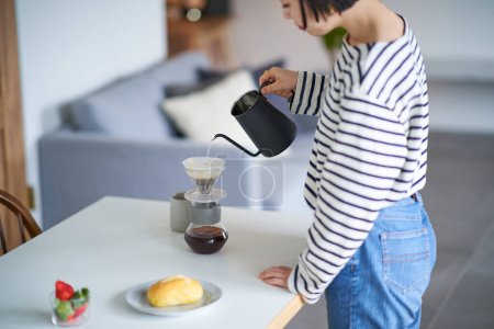 Foto de Mujer joven elaborando café en su habitación - Imagen libre de derechos