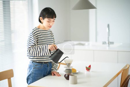 Téléchargez les photos : Jeune femme brassant du café dans sa chambre - en image libre de droit