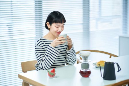 Téléchargez les photos : Jeune femme buvant du café dans la chambre - en image libre de droit
