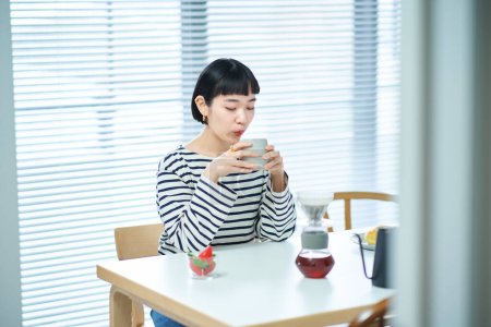 Téléchargez les photos : Jeune femme buvant du café dans la chambre - en image libre de droit