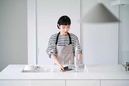 Foto de Mujer joven lavando platos en la cocina - Imagen libre de derechos