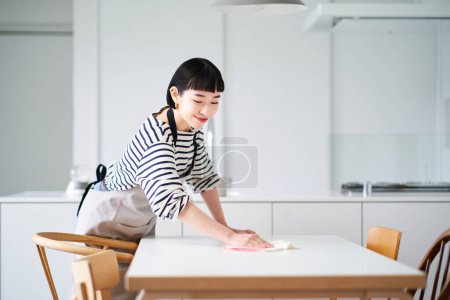 Photo for Young woman wiping the dining table - Royalty Free Image