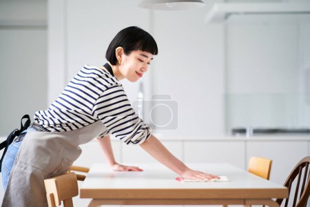 Foto de Mujer joven limpiando la mesa de comedor - Imagen libre de derechos