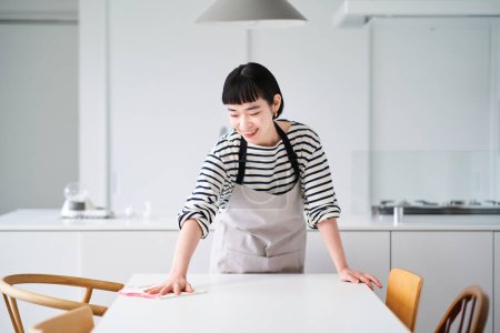 Foto de Mujer joven limpiando la mesa de comedor - Imagen libre de derechos