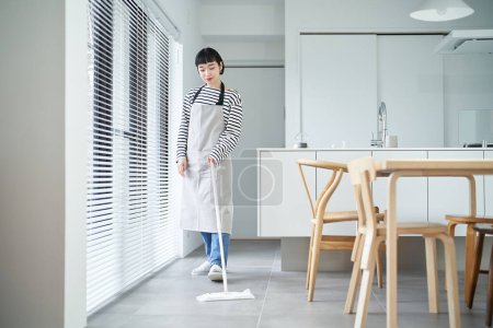Photo for Asian young woman cleaning the floor in the room - Royalty Free Image