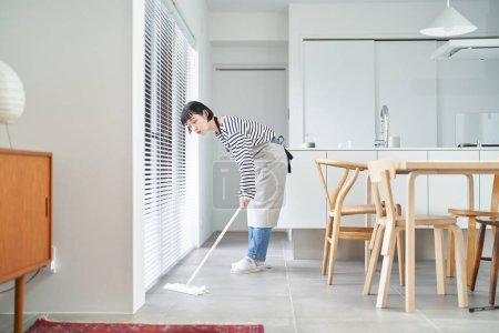 Téléchargez les photos : Asiatique jeune femme nettoyage le sol dans la chambre - en image libre de droit