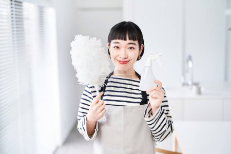 Téléchargez les photos : Jeune femme avec des outils de nettoyage dans la chambre - en image libre de droit