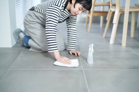 Téléchargez les photos : Jeune femme qui nettoie le sol dans la chambre - en image libre de droit