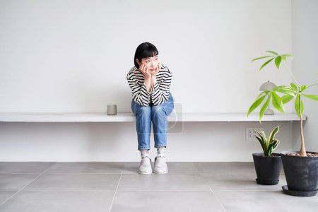 Téléchargez les photos : Une jeune femme se relaxant dans une chambre aux plantes d'intérieur - en image libre de droit