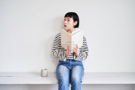 Téléchargez les photos : Jeune femme lisant le livre dans la chambre - en image libre de droit