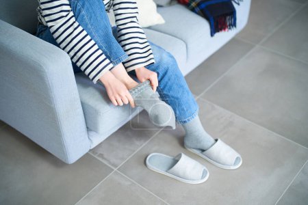 Photo for Young woman putting on socks in the room - Royalty Free Image