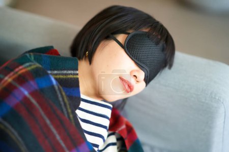 Photo for Young woman lying down with an eye mask in the room - Royalty Free Image