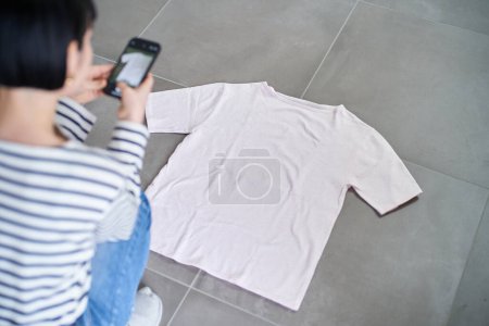 Photo for Young woman taking photos of clothes in the room - Royalty Free Image