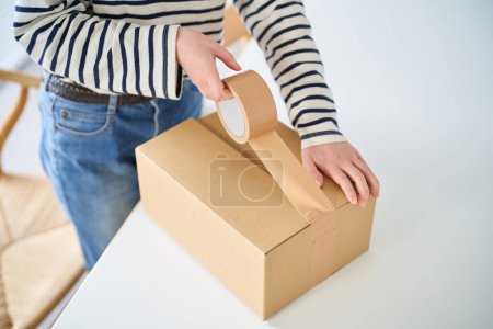 Mujer joven empacando una caja de cartón en la habitación
