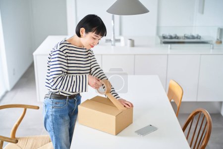 Photo for Young woman packing a cardboard box in the room - Royalty Free Image