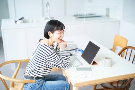 Téléchargez les photos : Jeune femme avec des lunettes de travail à table dans la chambre - en image libre de droit