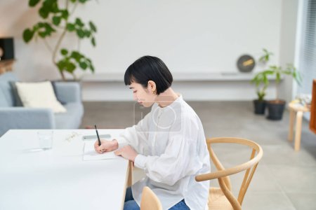 Foto de Mujer joven escribiendo en cuaderno en la habitación - Imagen libre de derechos